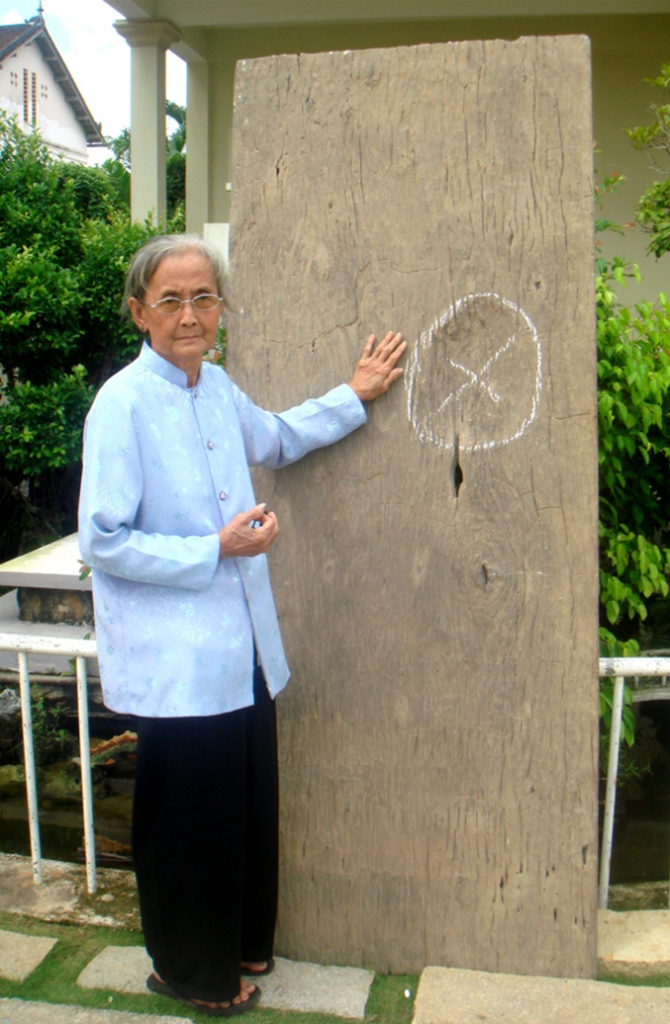 Bà Tám (vợ của ông Biện Nguyễn Văn Nhung) và tấm ván hiện giờ. Ảnh chụp ngày 8 / 10 / 2011, tại khuôn viên nhà thờ Cái Mơn.